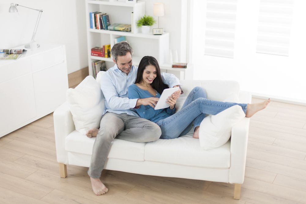 Couple Relaxing on a White Sofa, Looking at a Tablet — Clarity Family Therapy in Brisbane, QLD