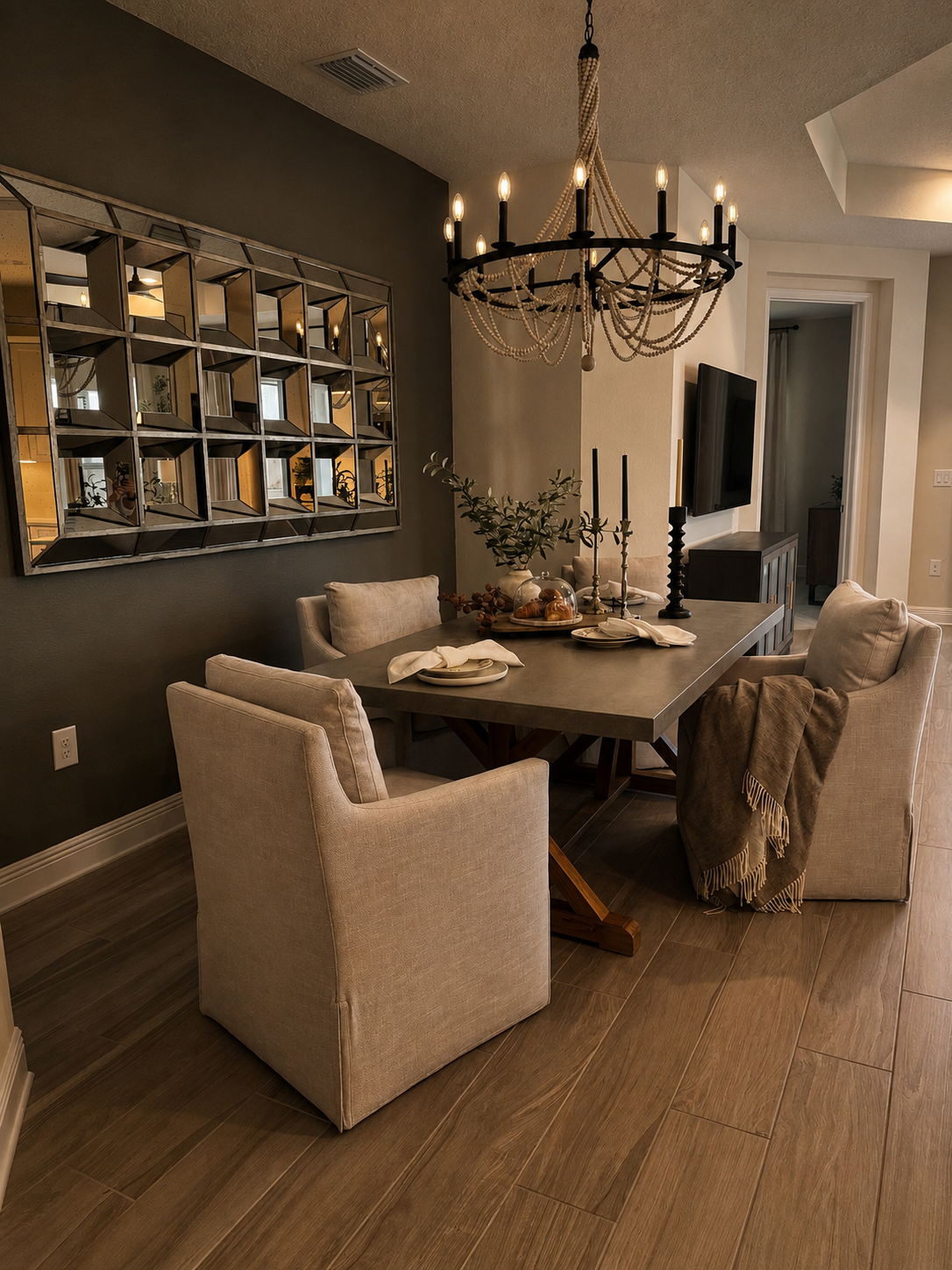 Modern dining room with dark walls, wooden table, beige chairs, and a black chandelier