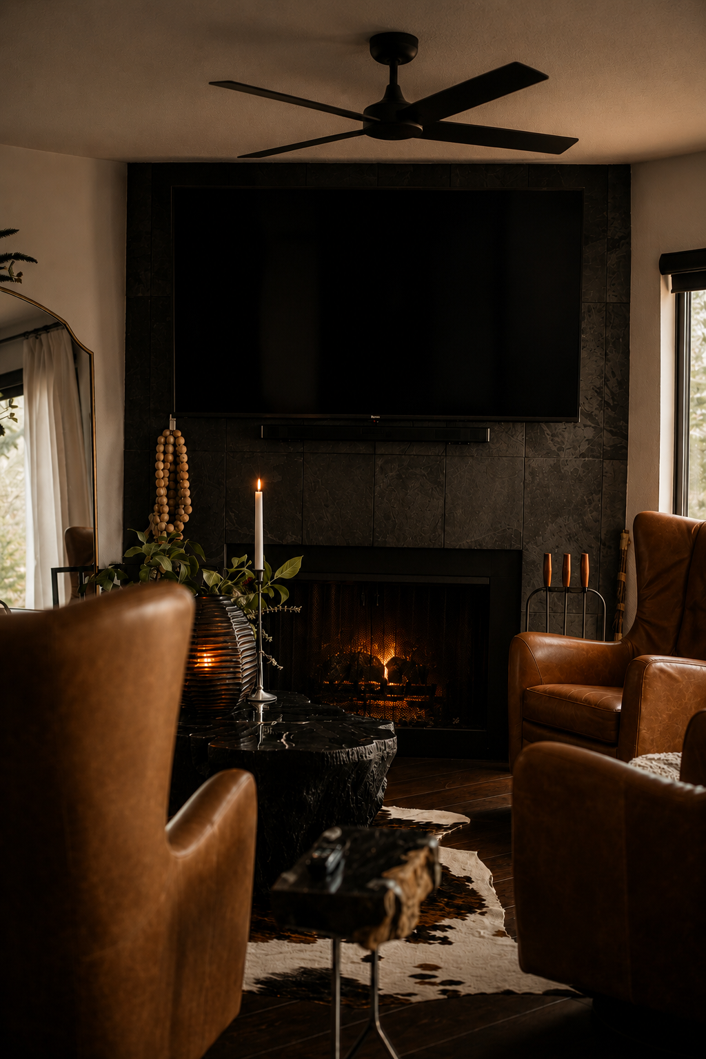 Cozy living room with leather chairs, a lit fireplace, and a large wall-mounted TV
