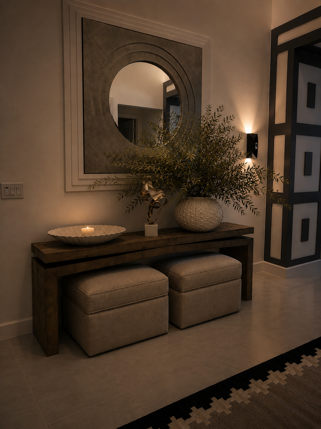 Elegant entryway with console table, round mirror, potted greenery, stools, and wall sconce lighting