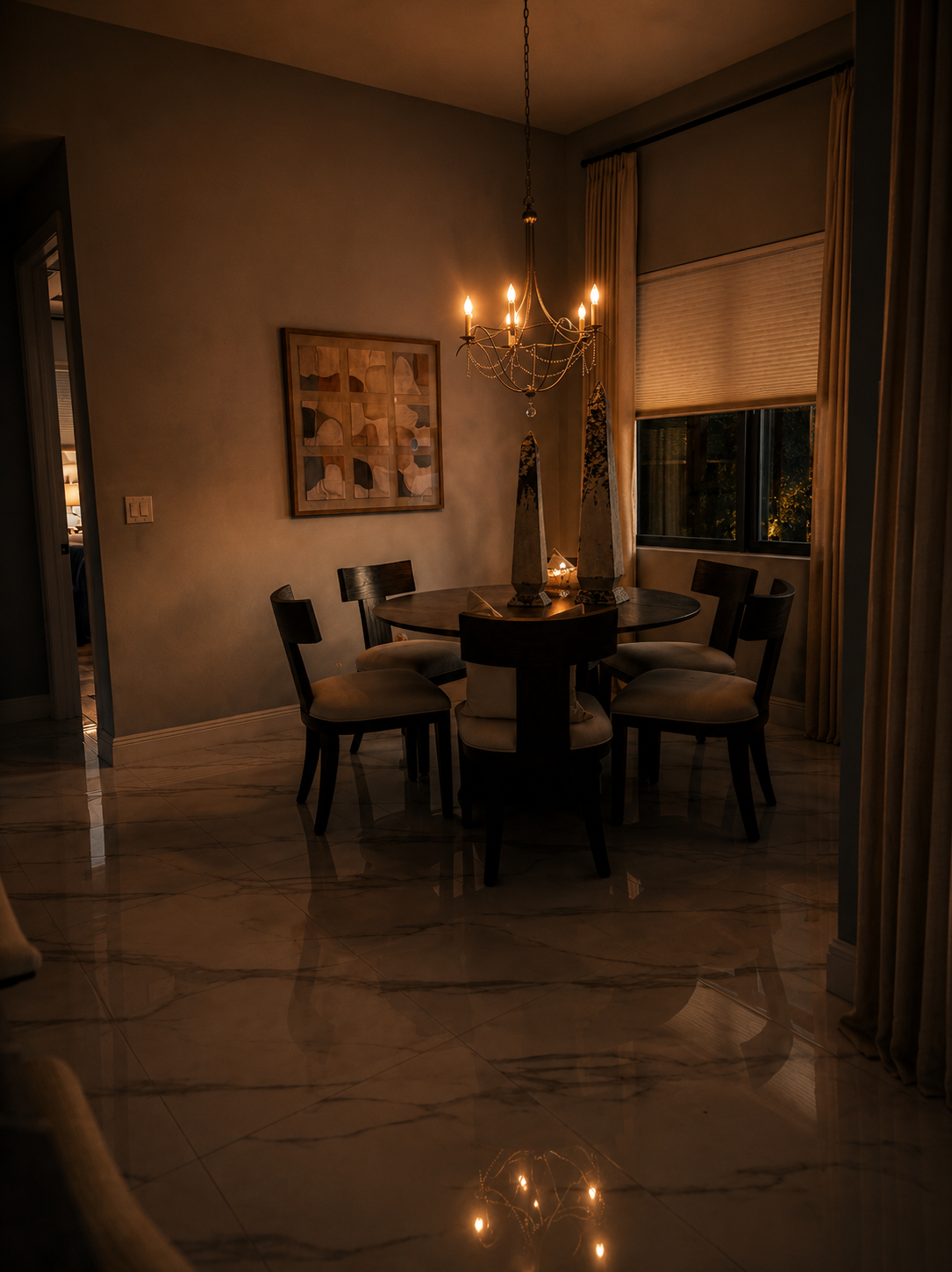 Dim dining room with a round table, chandelier, and draped curtains by a window.