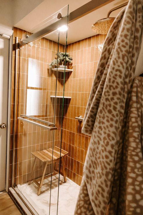 Tall metal shelving unit in a warm-toned room with hanging string lights and a patterned curtain beside it