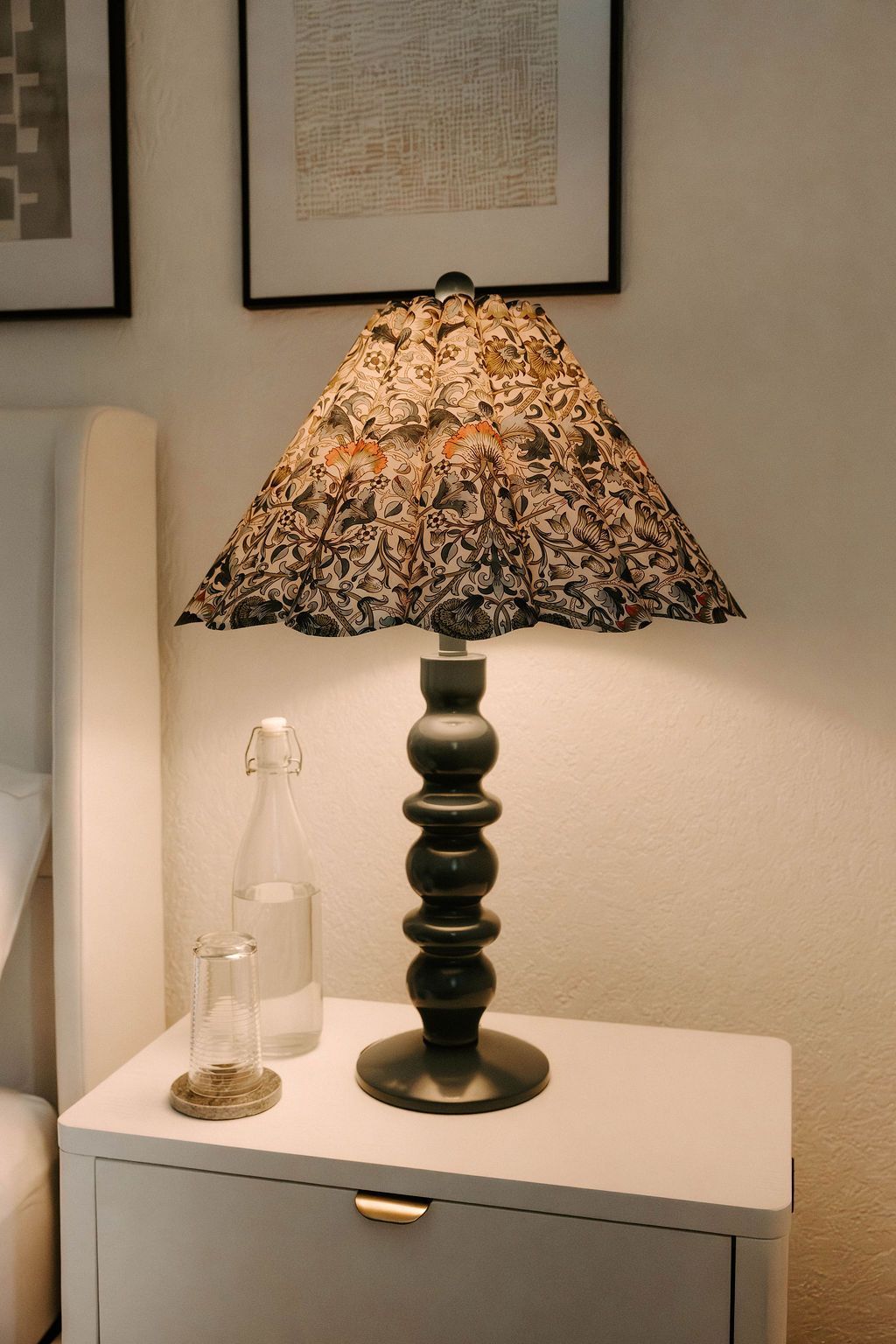 Decorative table lamp with patterned shade on a white side table in a softly lit room