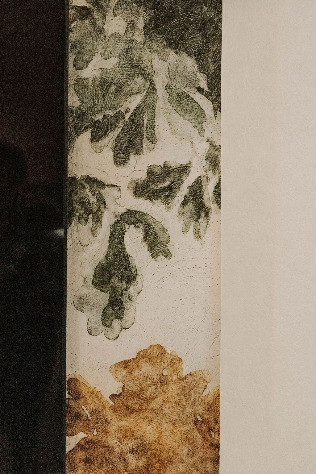 Textured vertical artwork with green leafy shapes above and a brown floral pattern below on a light background
