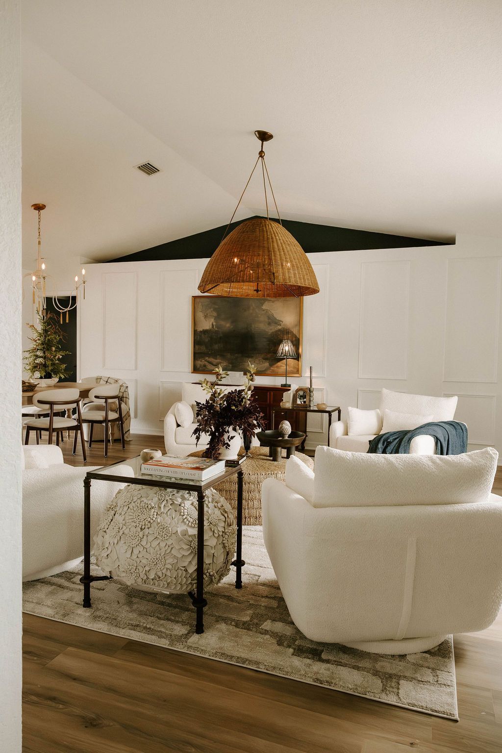 Elegant living room with white chairs, woven pendant light, fireplace, and dark wood flooring
