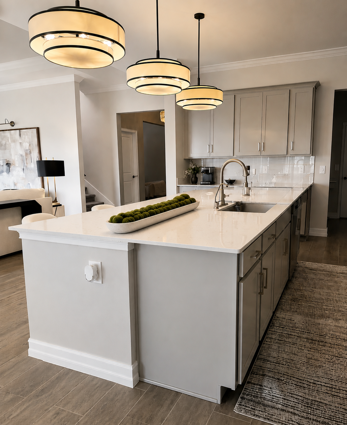 Modern kitchen with large white island, pendant lights, gray cabinets, and marble countertops
