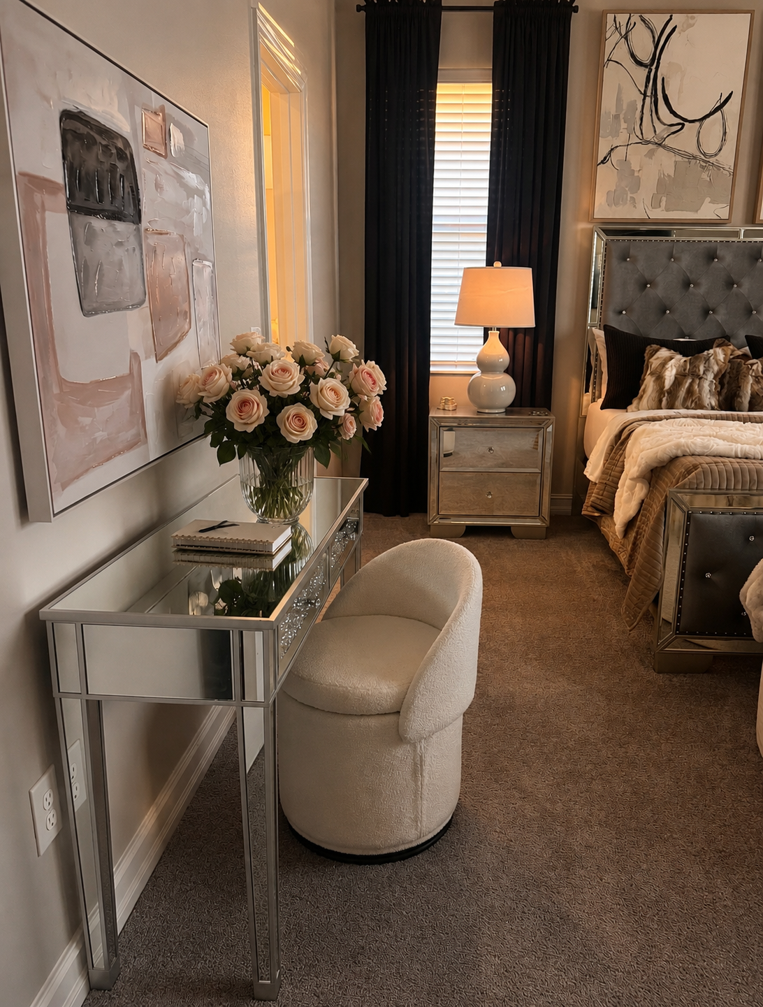 Elegant bedroom with mirrored desk, cream stool, floral bouquet, bedside lamp, and upholstered bed