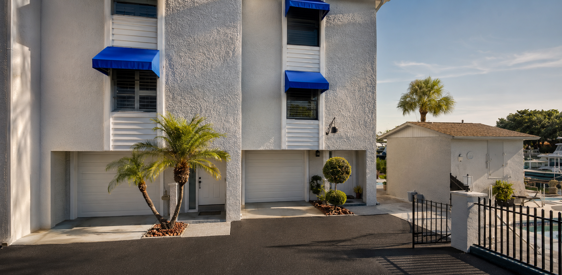 Dark-themed bathroom with toilet, double vanity, round mirrors, and potted plant