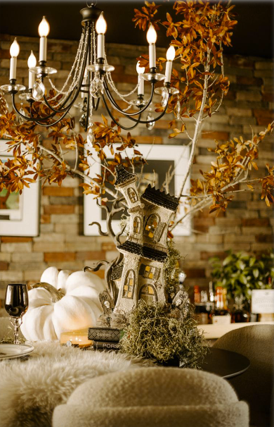 Elegant dining room with chandelier, autumn leaves, pumpkins, and candles on a decorated table
