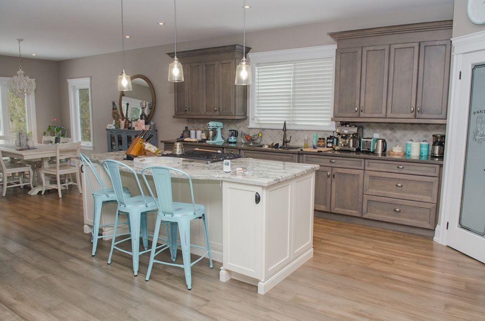 Bright kitchen with white island, light wood cabinets, and aqua chairs on hardwood floors