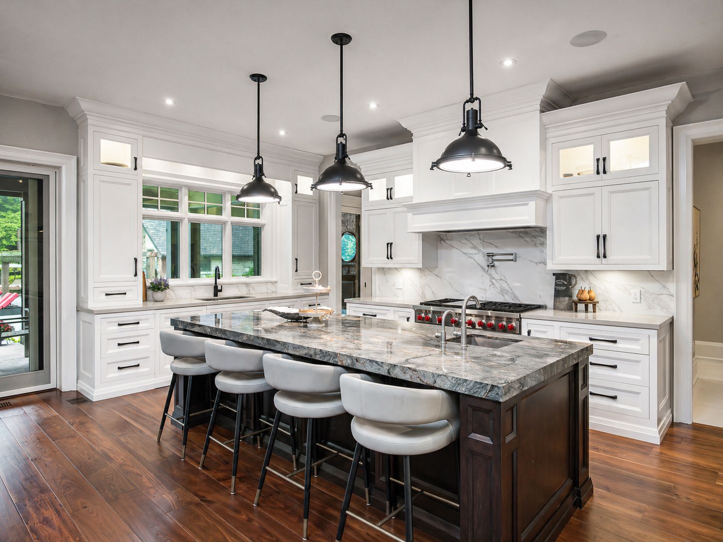 Modern kitchen with large island, white cabinets, pendant lights, and hardwood floors