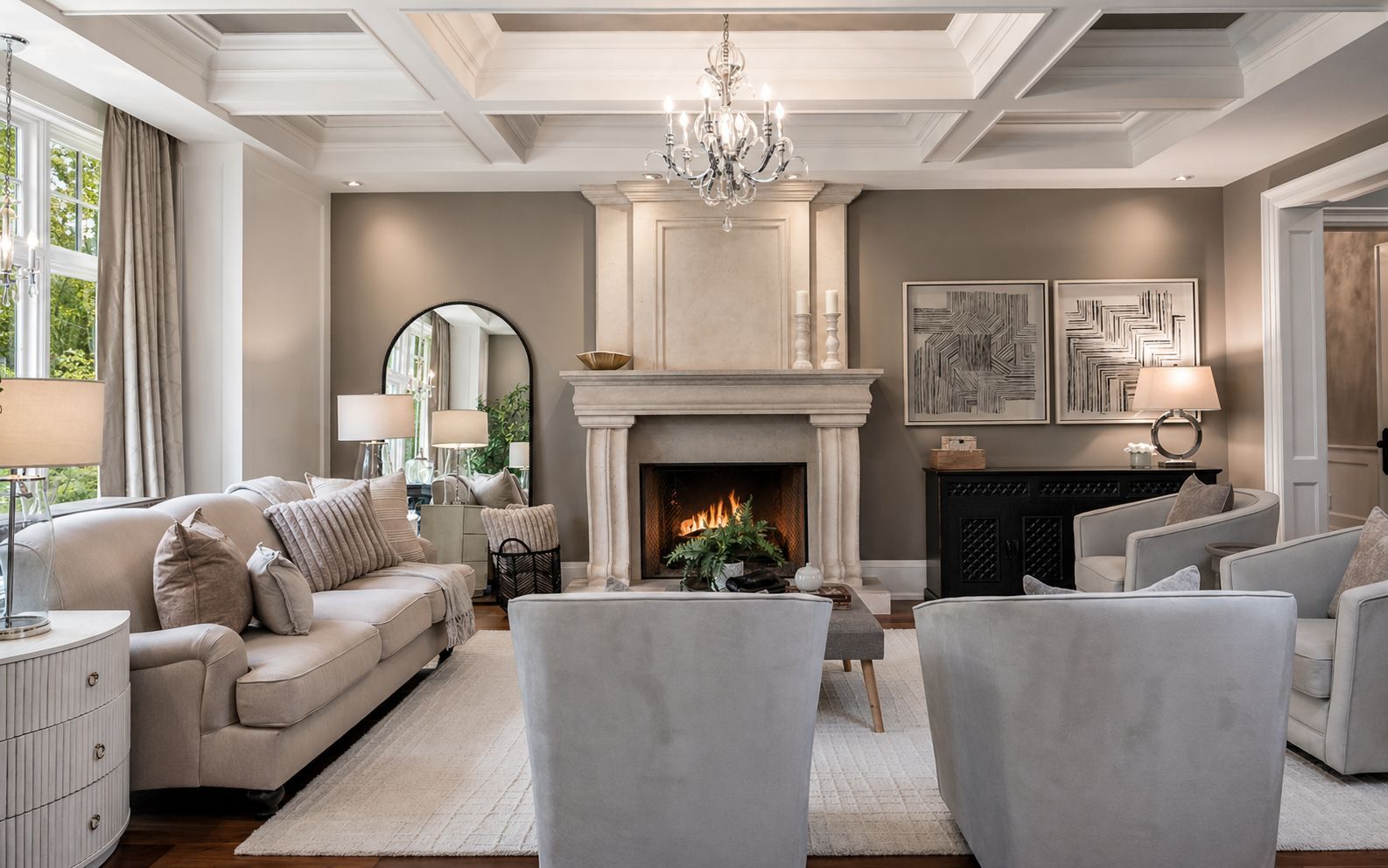 Elegant living room with fireplace, chandelier, beige sofas, and soft neutral decor