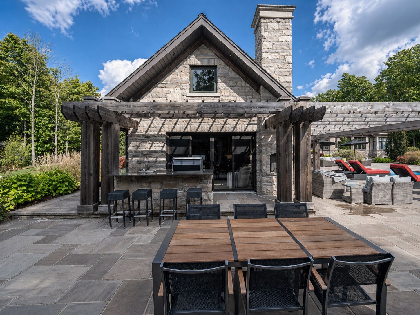 Stone patio with outdoor dining tables in front of a rustic lodge under a blue sky.