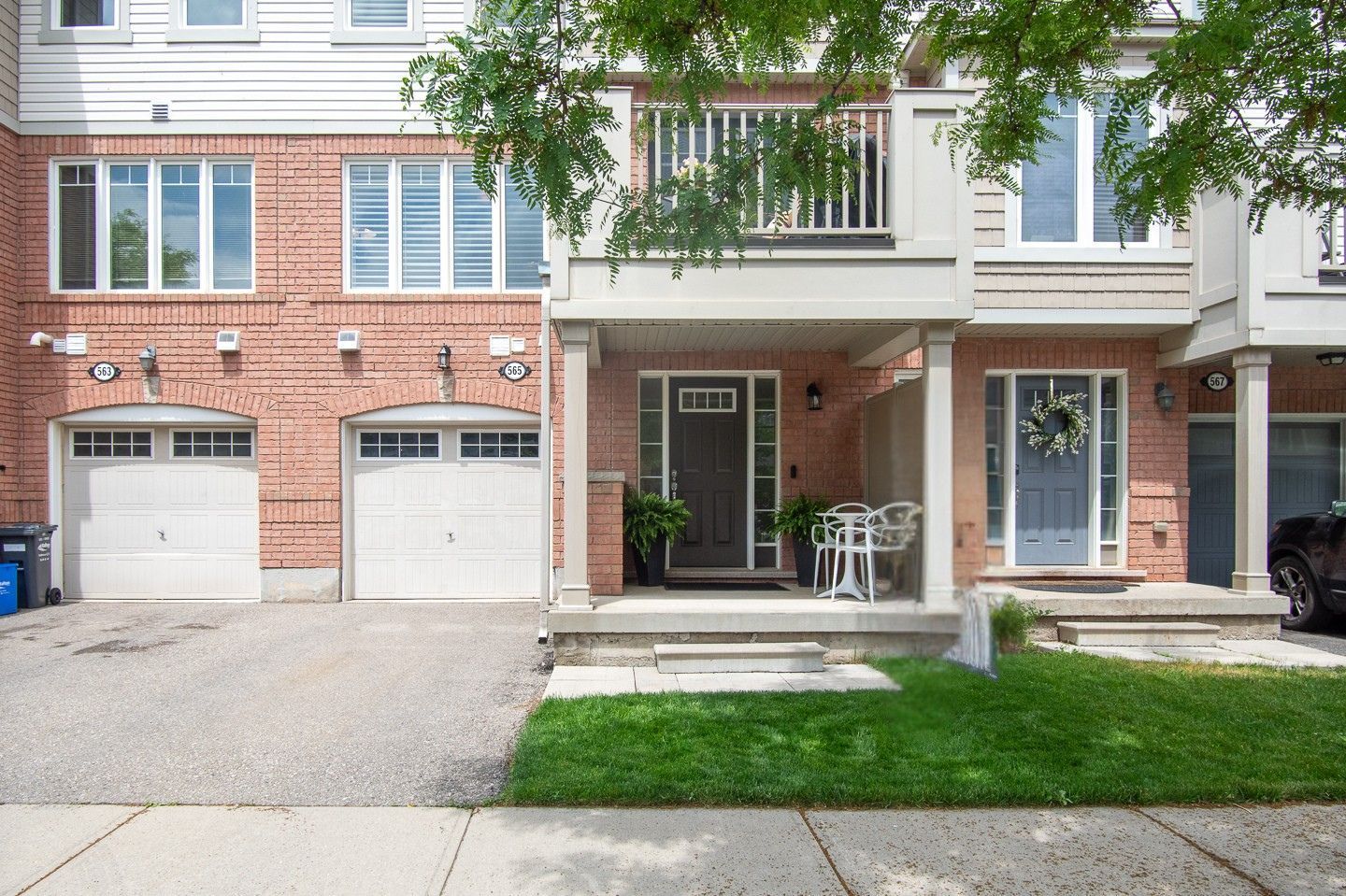 Townhouse row with garages, brick and beige facades, and a small front porch with green lawn.
