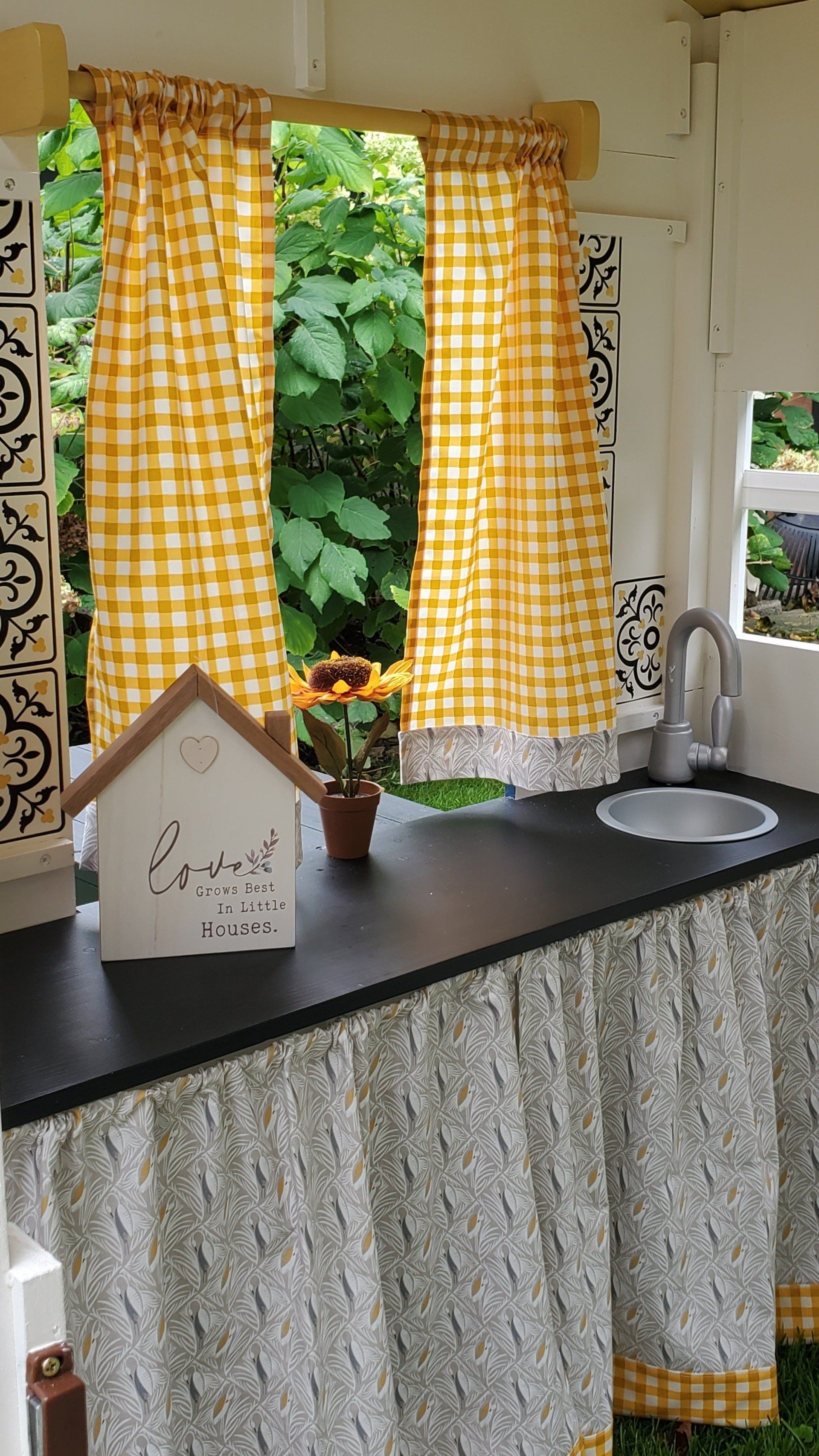 A kitchen with yellow checkered curtains and a sink.