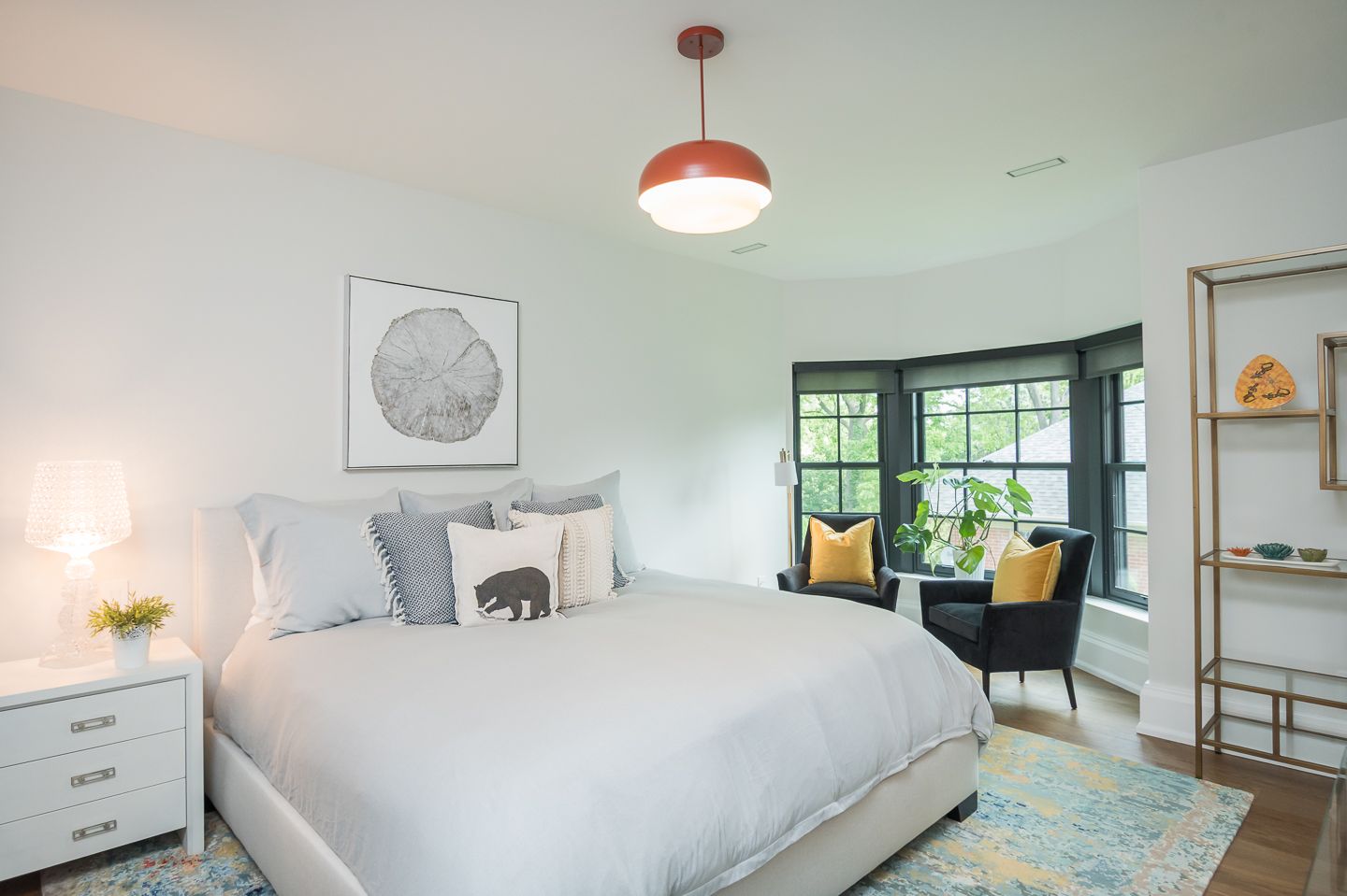 A bedroom with a king size bed , chair , nightstand and window.
