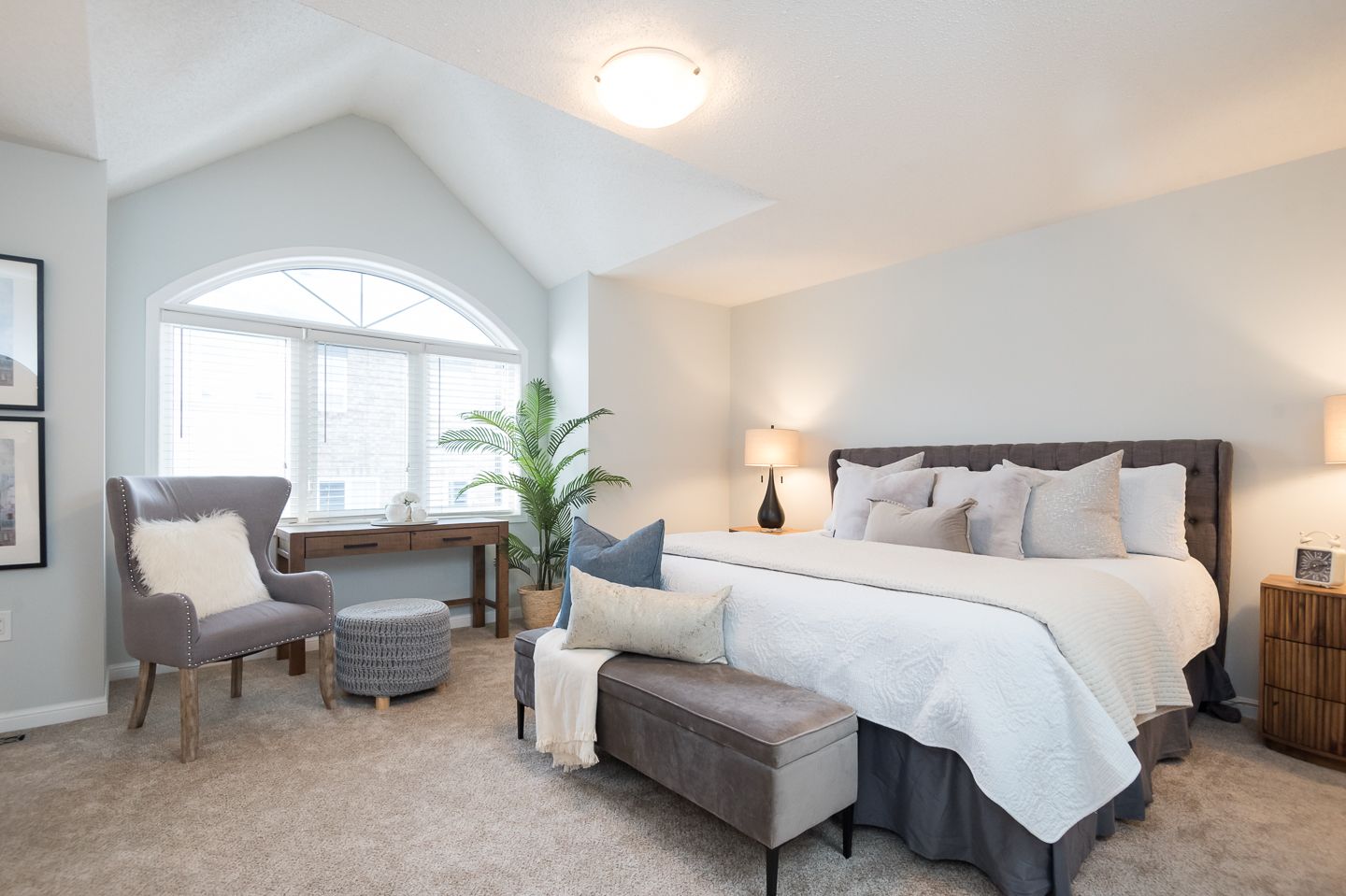 Spacious bedroom with a bed, seating area by a large window, and neutral tones.