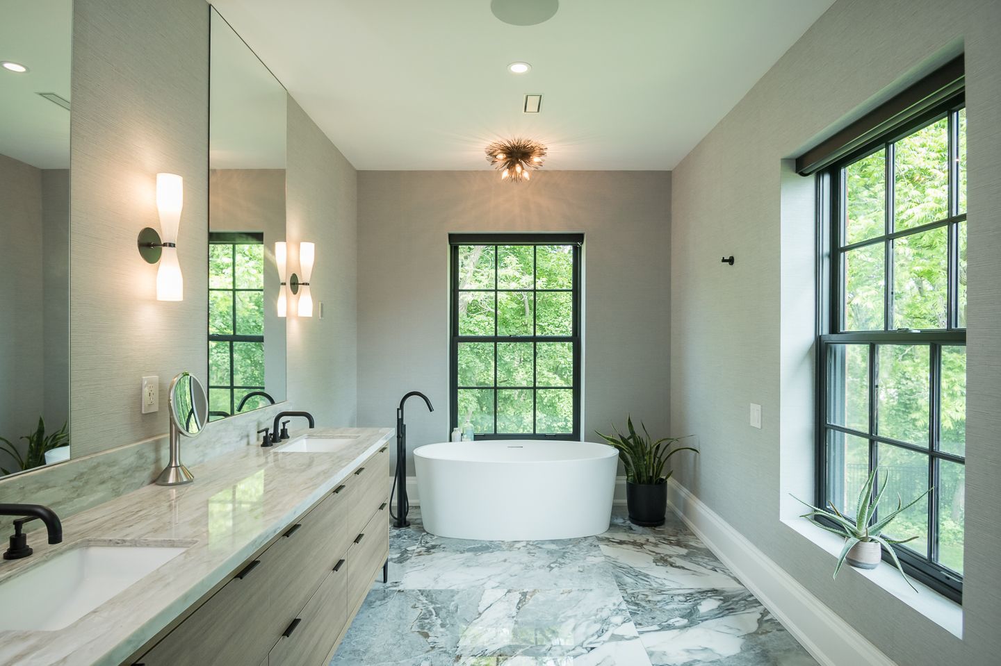 A bathroom with two sinks , a tub , and two windows.