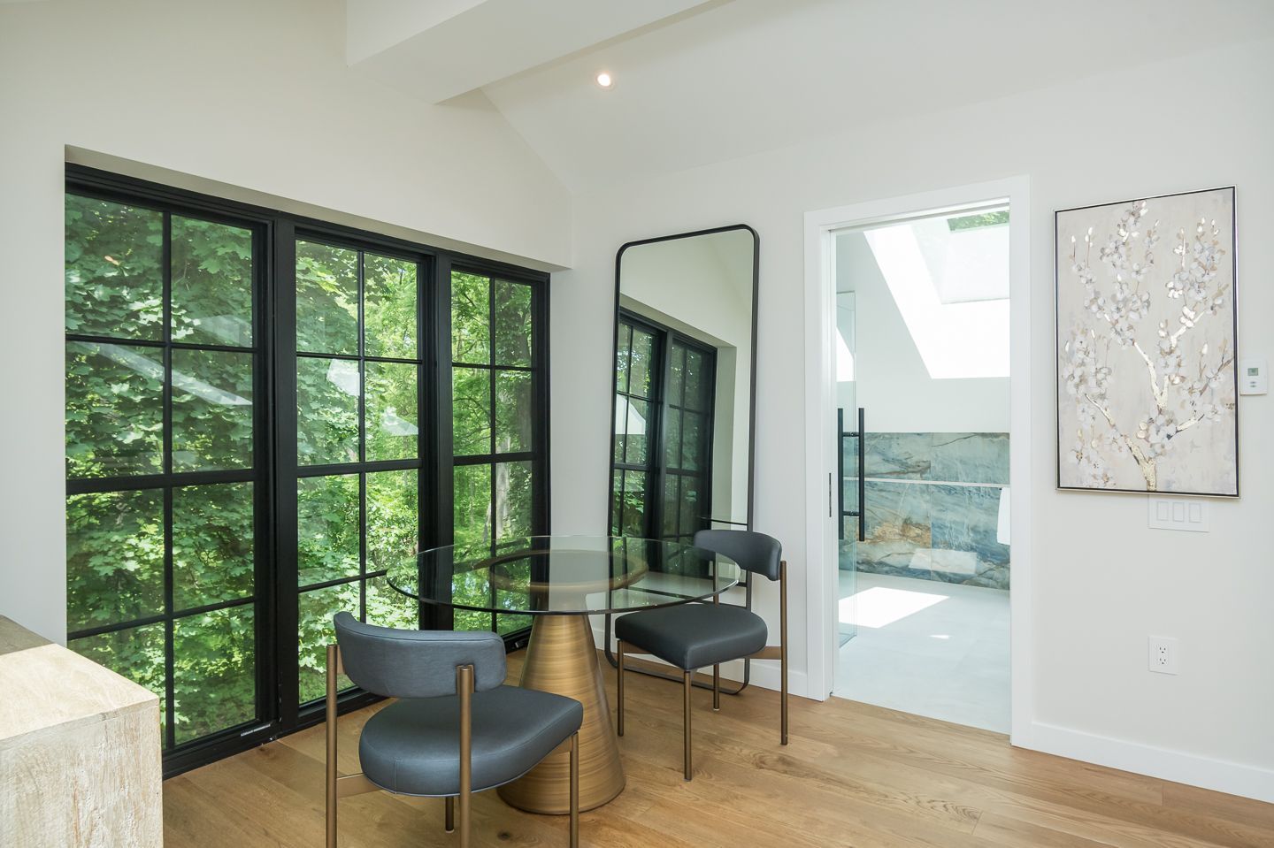 A room with a table and chairs and a large mirror.