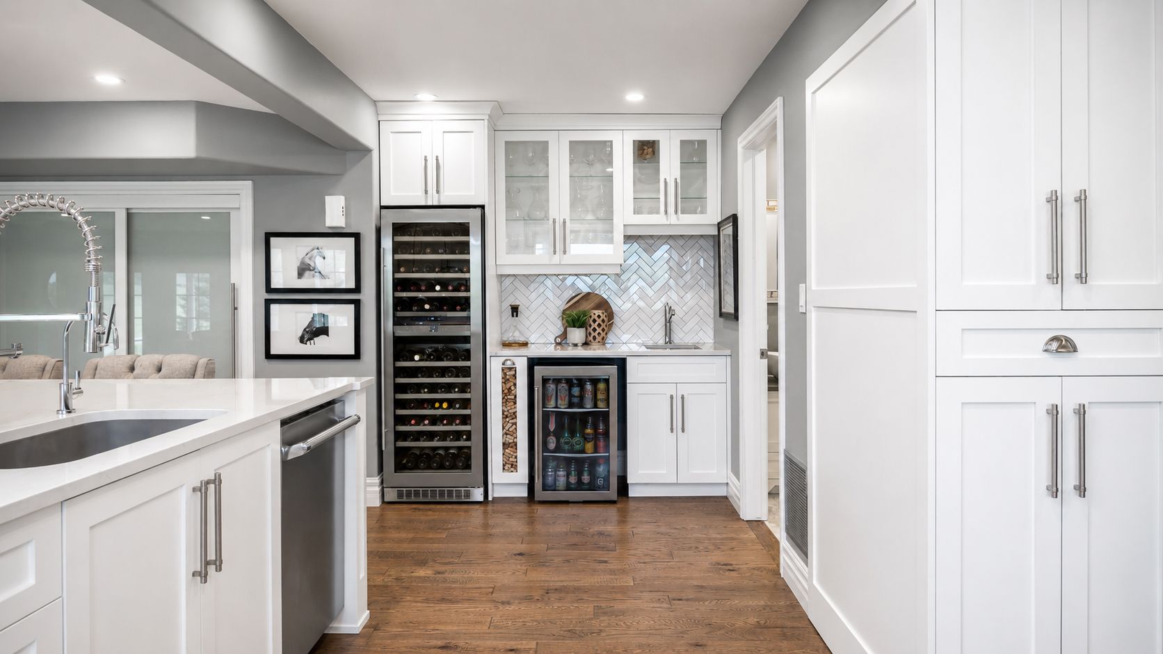 Bright white kitchen with glass cabinets, wine fridge, and wood flooring