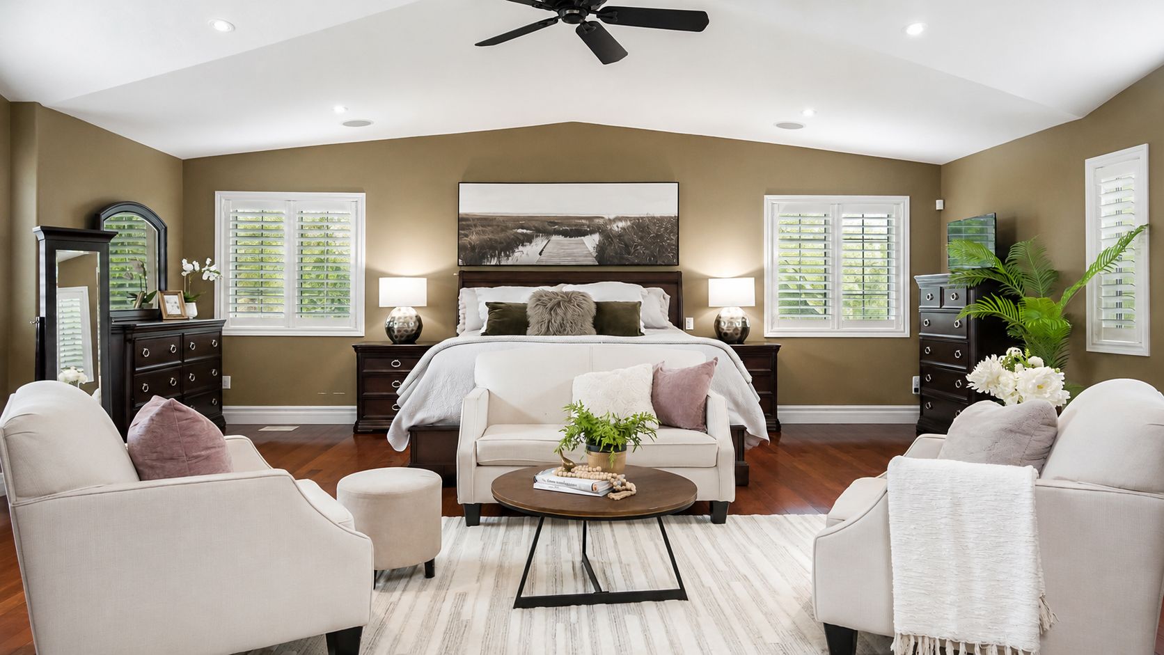 Bright modern bedroom with a centered bed, white chairs, wood accents, and large windows.