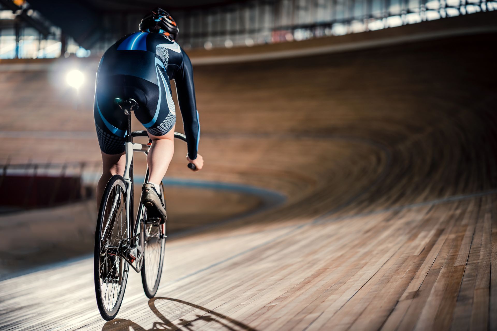 A man is riding a bike on a track in a velodrome.