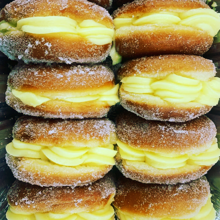 A bunch of doughnuts stacked on top of each other with yellow frosting