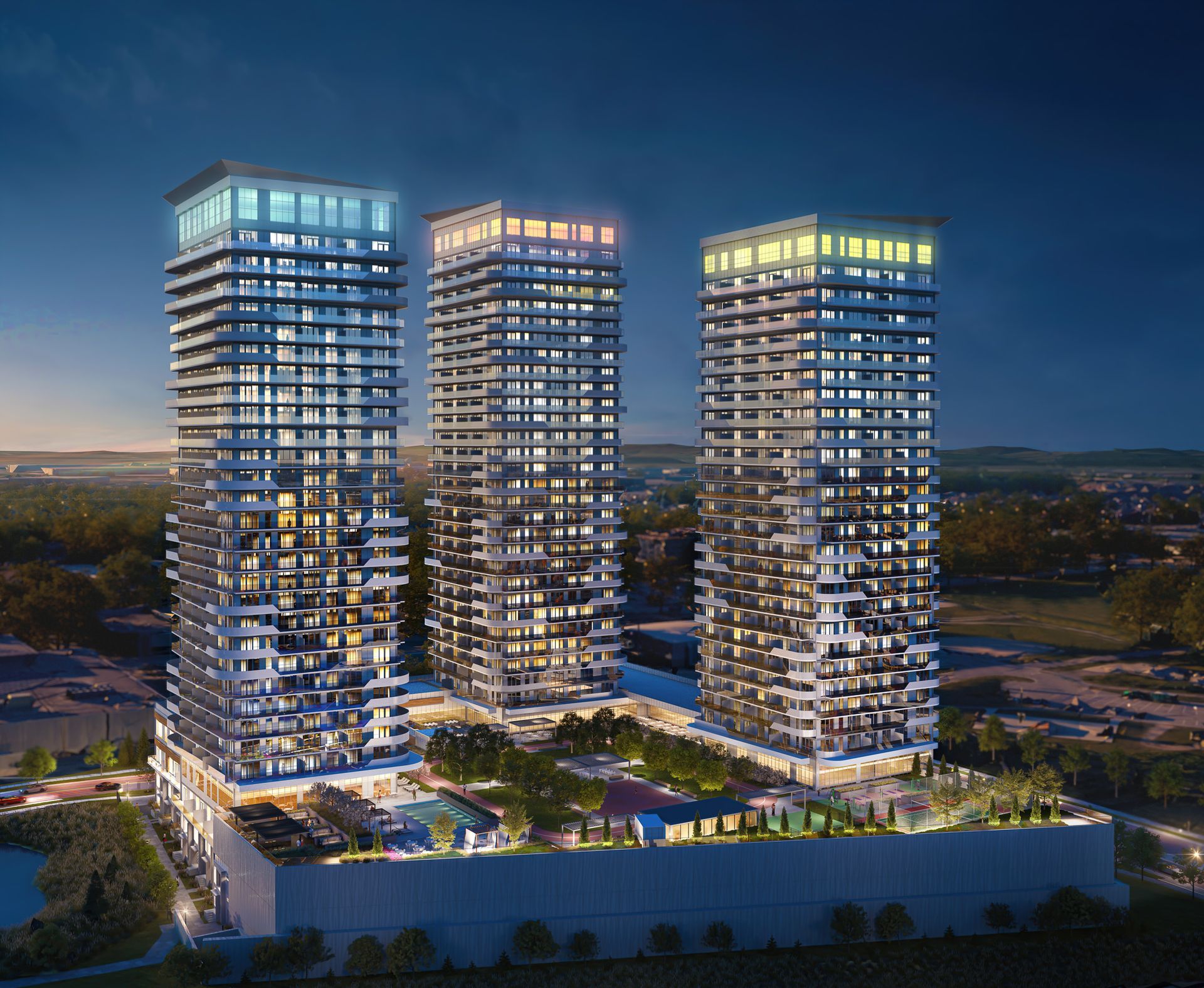 Three illuminated high-rise apartment towers with a landscaped podium, pool, and green space, at dusk.