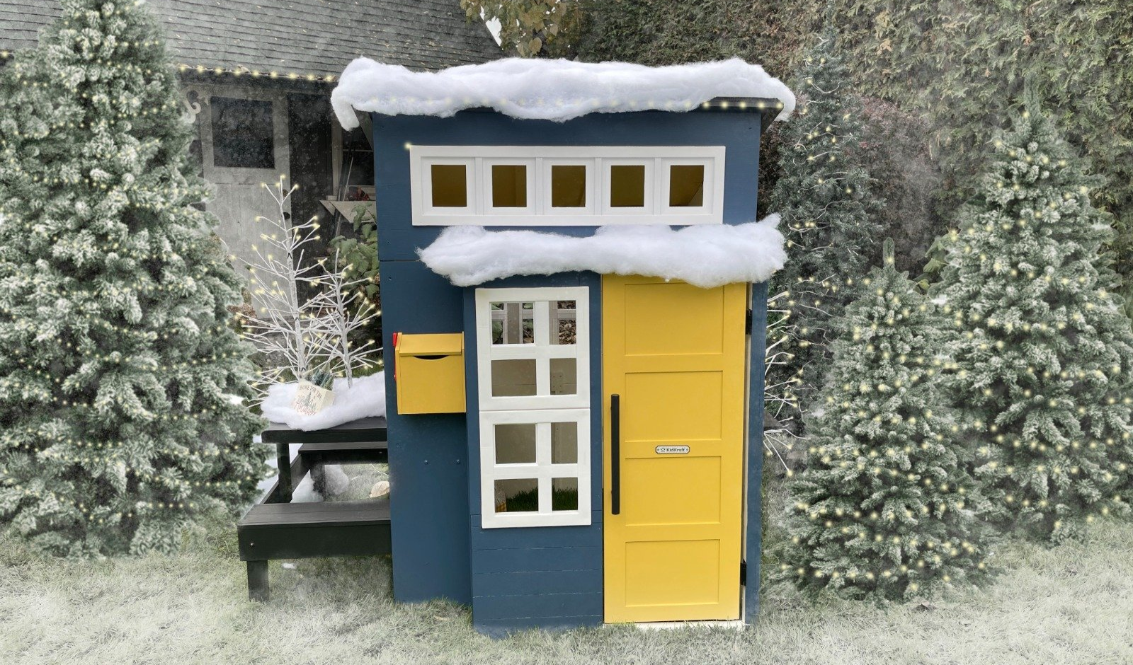 A blue and yellow playhouse with snow on the roof