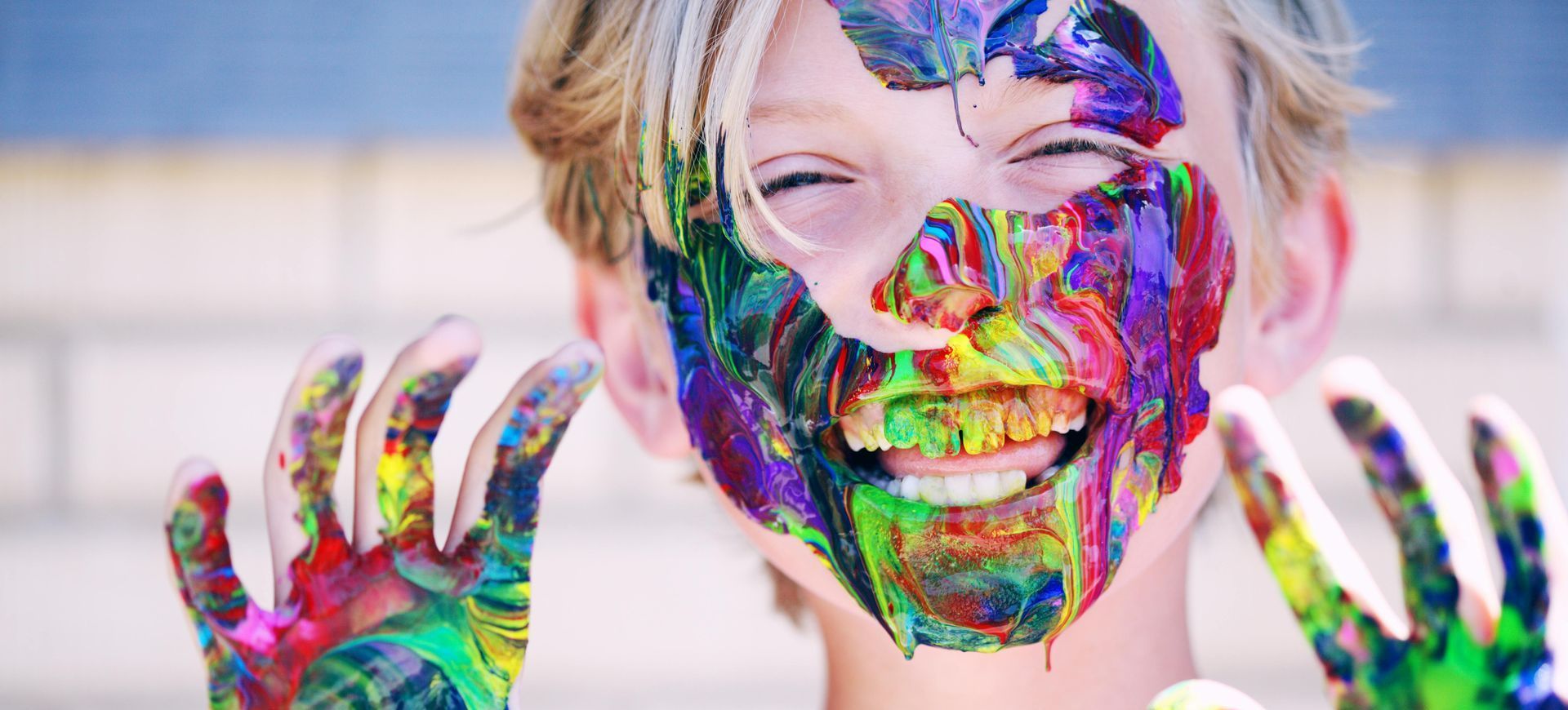A young boy with paint on his face and hands.