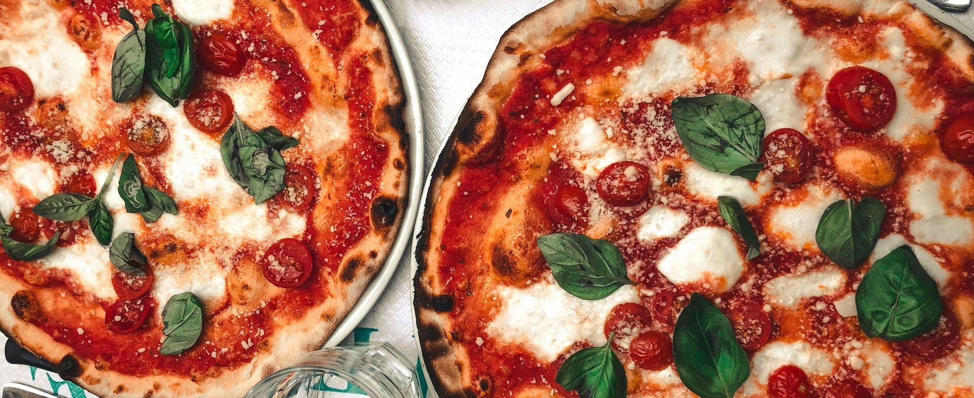 Two pizzas are sitting on top of each other on a table.