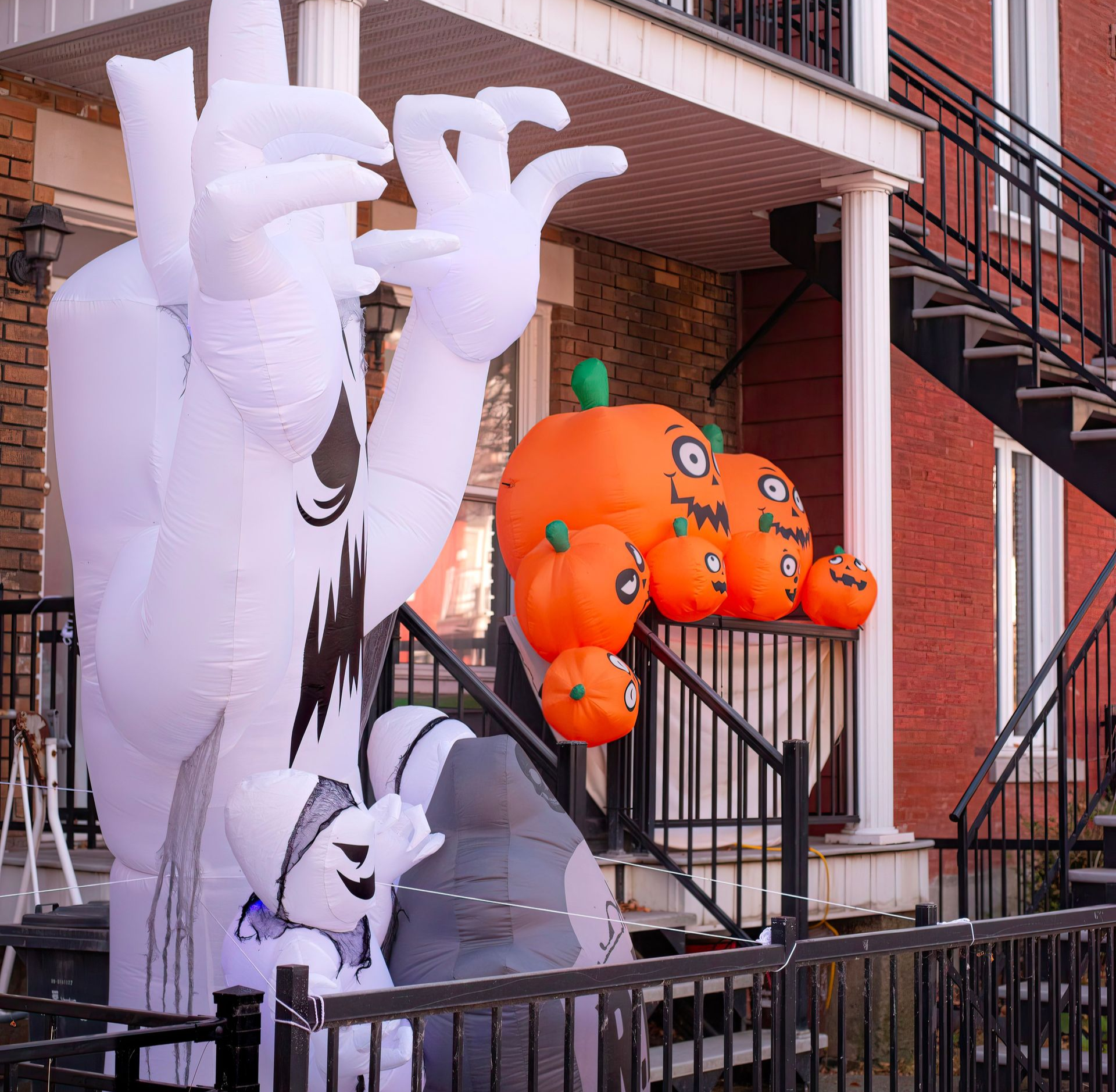 White inflatable ghost and orange pumpkin Halloween decorations on an apartment stairway￼