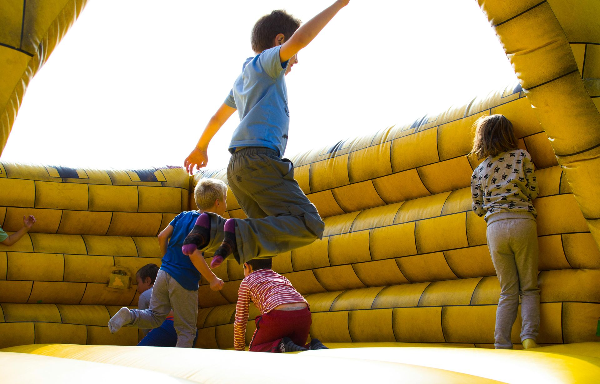 Children climbing on a yellow inflatable obstacle course outdoors