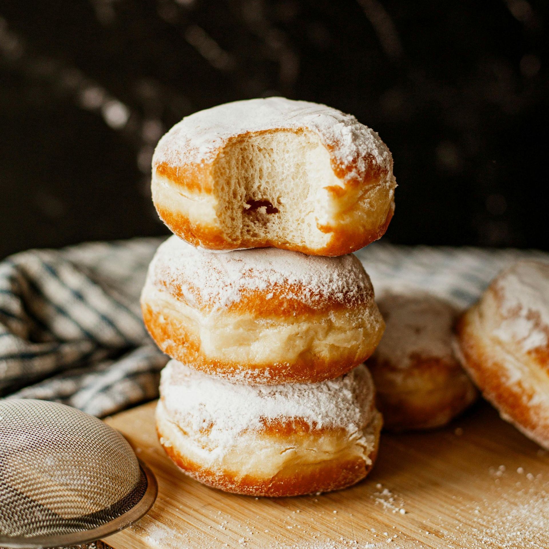 Three donuts are stacked on top of each other on a wooden table.