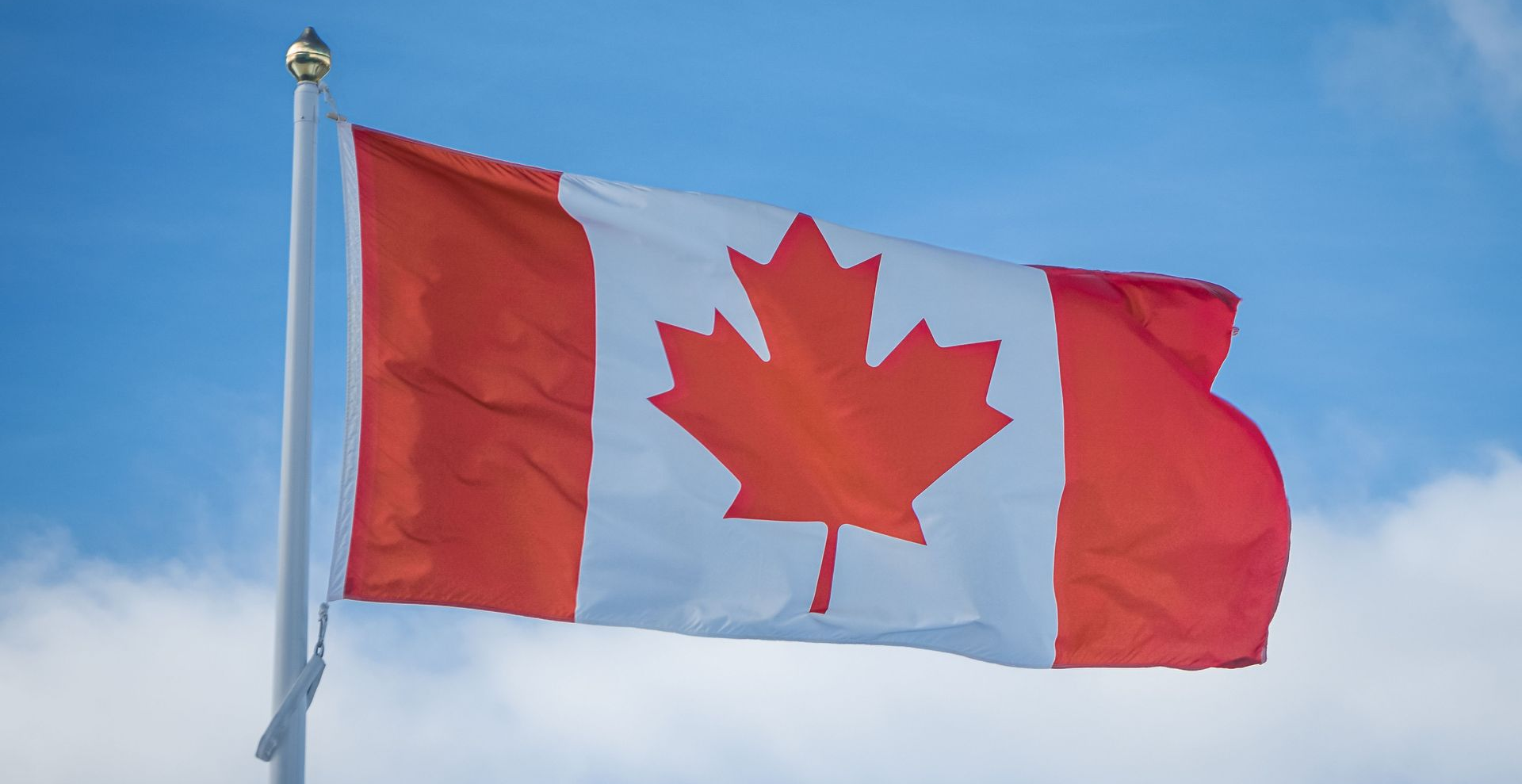 Canadian flag waving against a blue sky