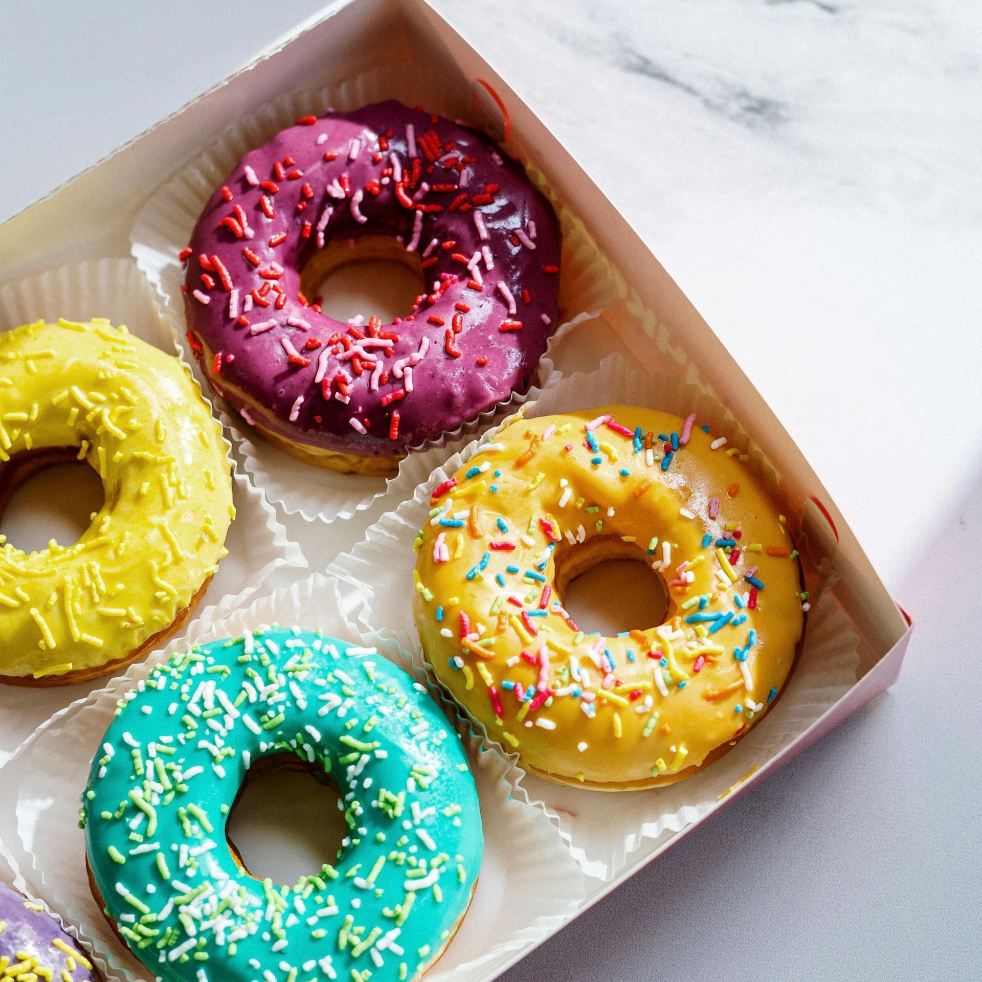 A box of colorful donuts with sprinkles on them