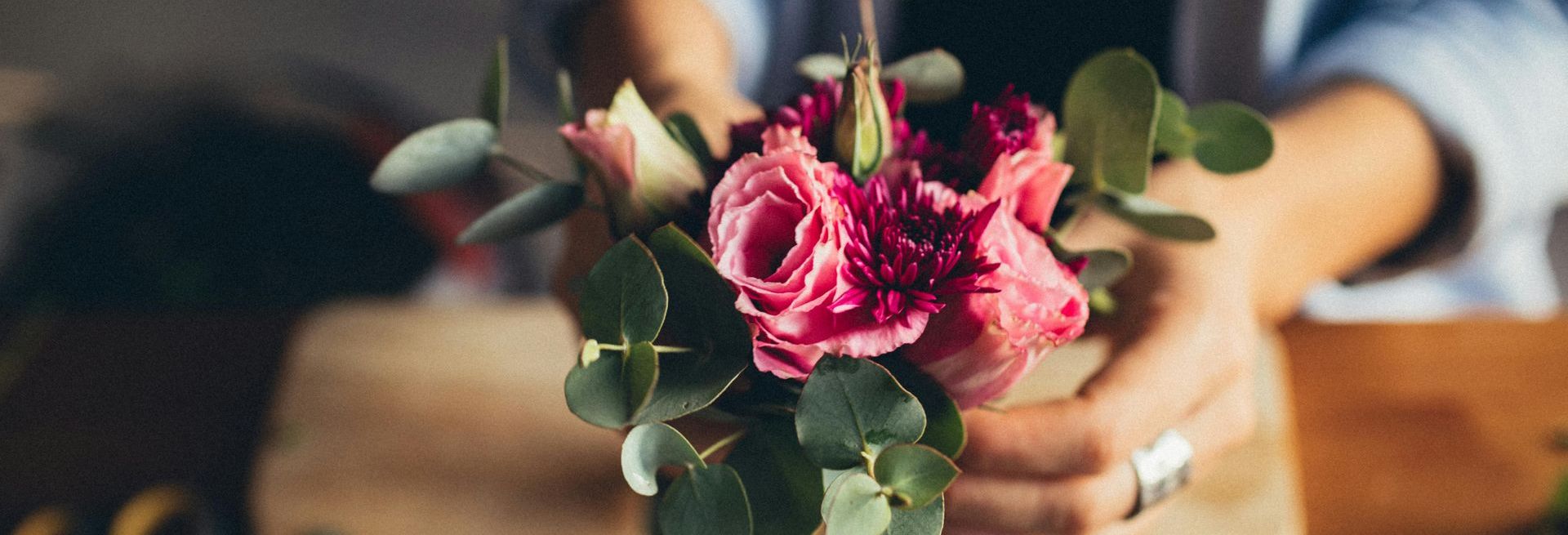 A person is holding a bouquet of pink flowers in their hands.