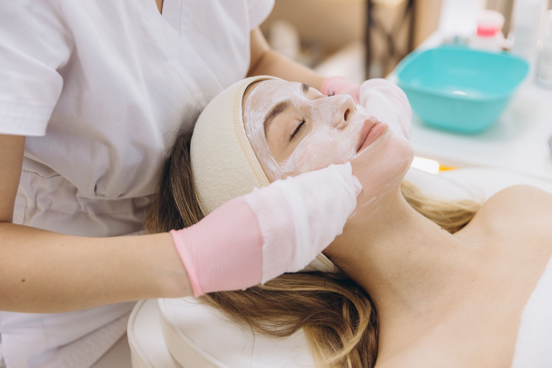 Facial treatment in a spa, with a woman lying back while a gloved therapist applies skincare.