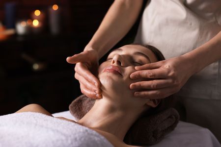 Spa therapist giving a facial massage to a client on a treatment table