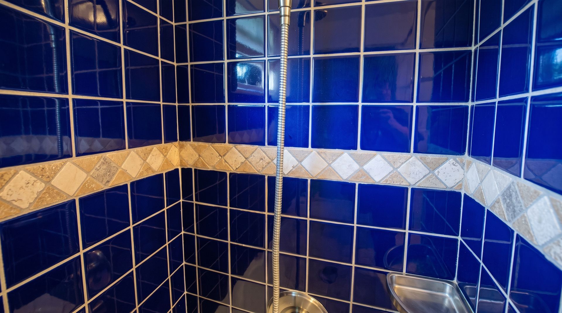 Modern white tiled shower with black fixtures and a patterned decorative tile strip