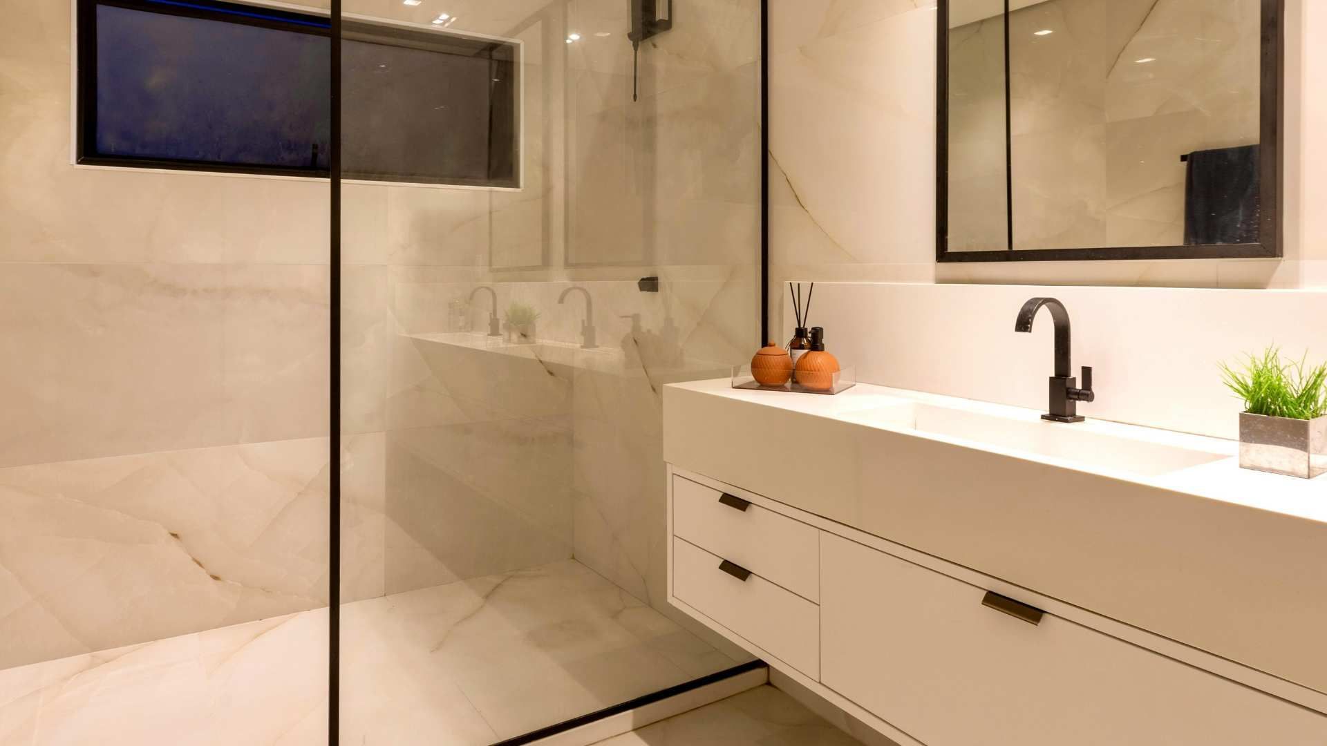 Modern bathroom with glass shower, floating vanity, large mirror, and beige tile walls