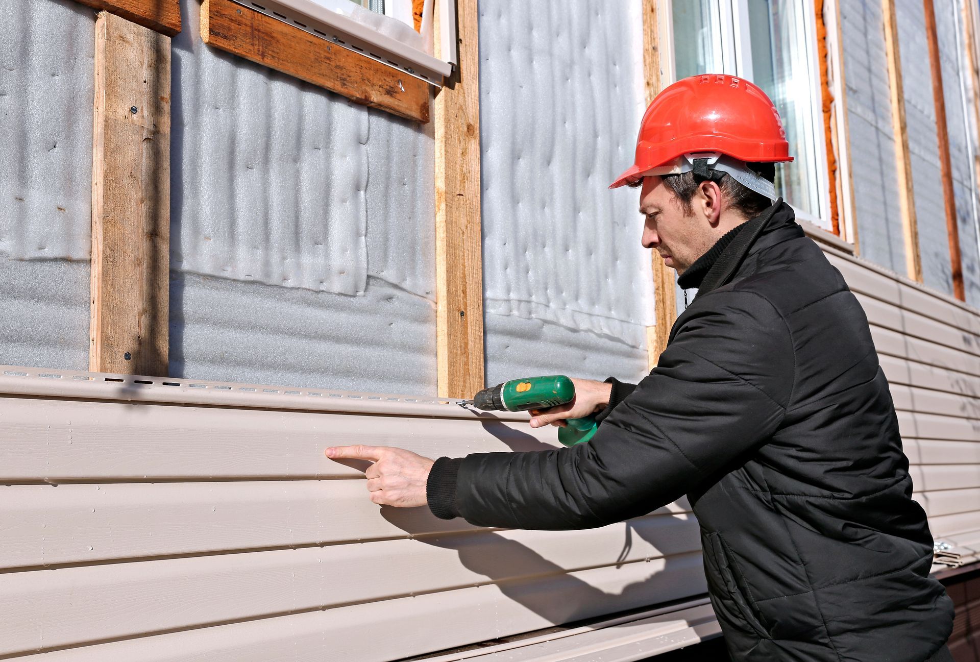 Contractor installing vinyl siding panels on a home exterior.