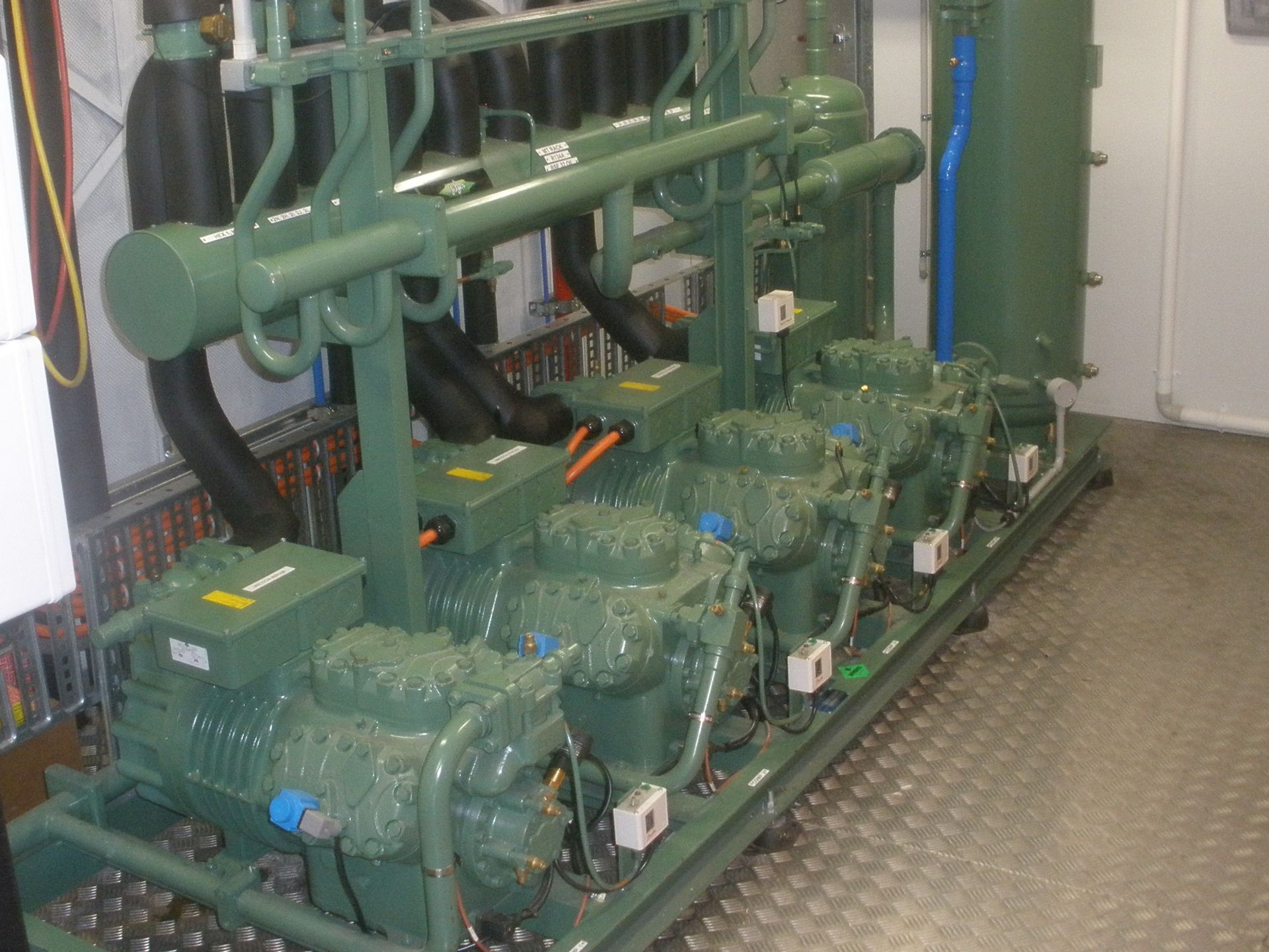 A row of green compressors are lined up in a room