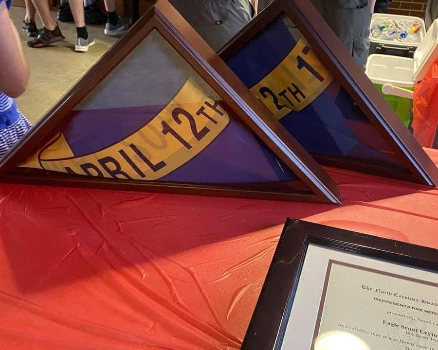 Framed triangular display pieces on a red table, one showing a purple-and-gold banner with text and numbers
