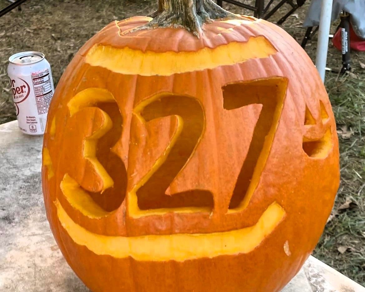 Orange pumpkin carved with “327” and a smiling face