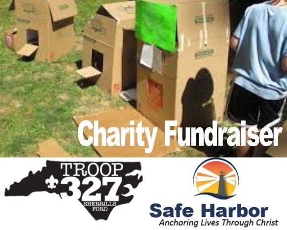 Cardboard houses on grass for charity fundraiser, with Troop 327 and Safe Harbor logos