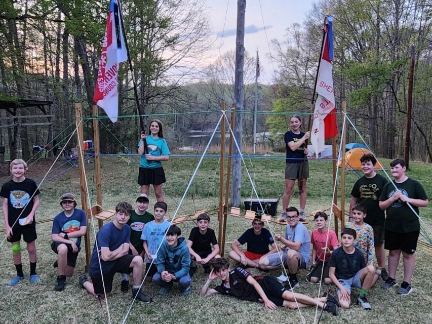 A group of young people are posing for a picture in front of a tent.