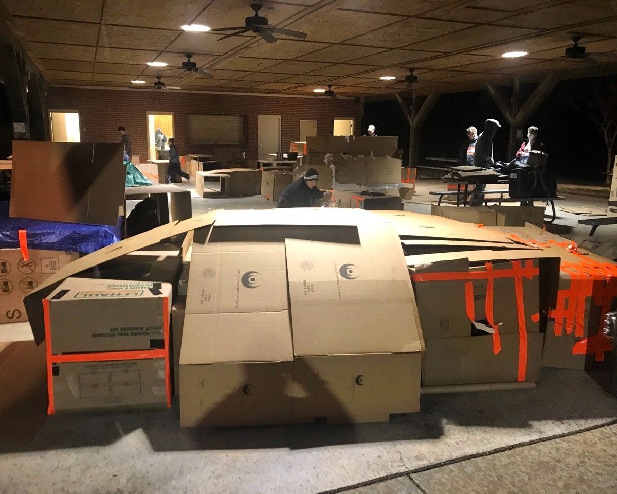 Cardboard fort-like structure with orange tape in a dim indoor room