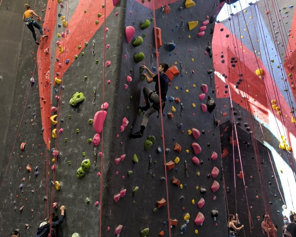 Indoor rock climbing wall with colorful holds and two climbers ascending ropes