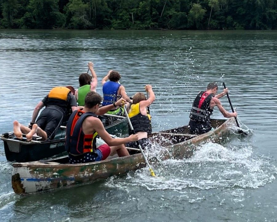 People paddling a dragon boat on a river, splashing water during a race